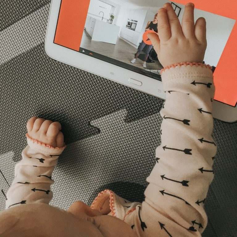 Baby trykker på iPad med efterfødselstræning